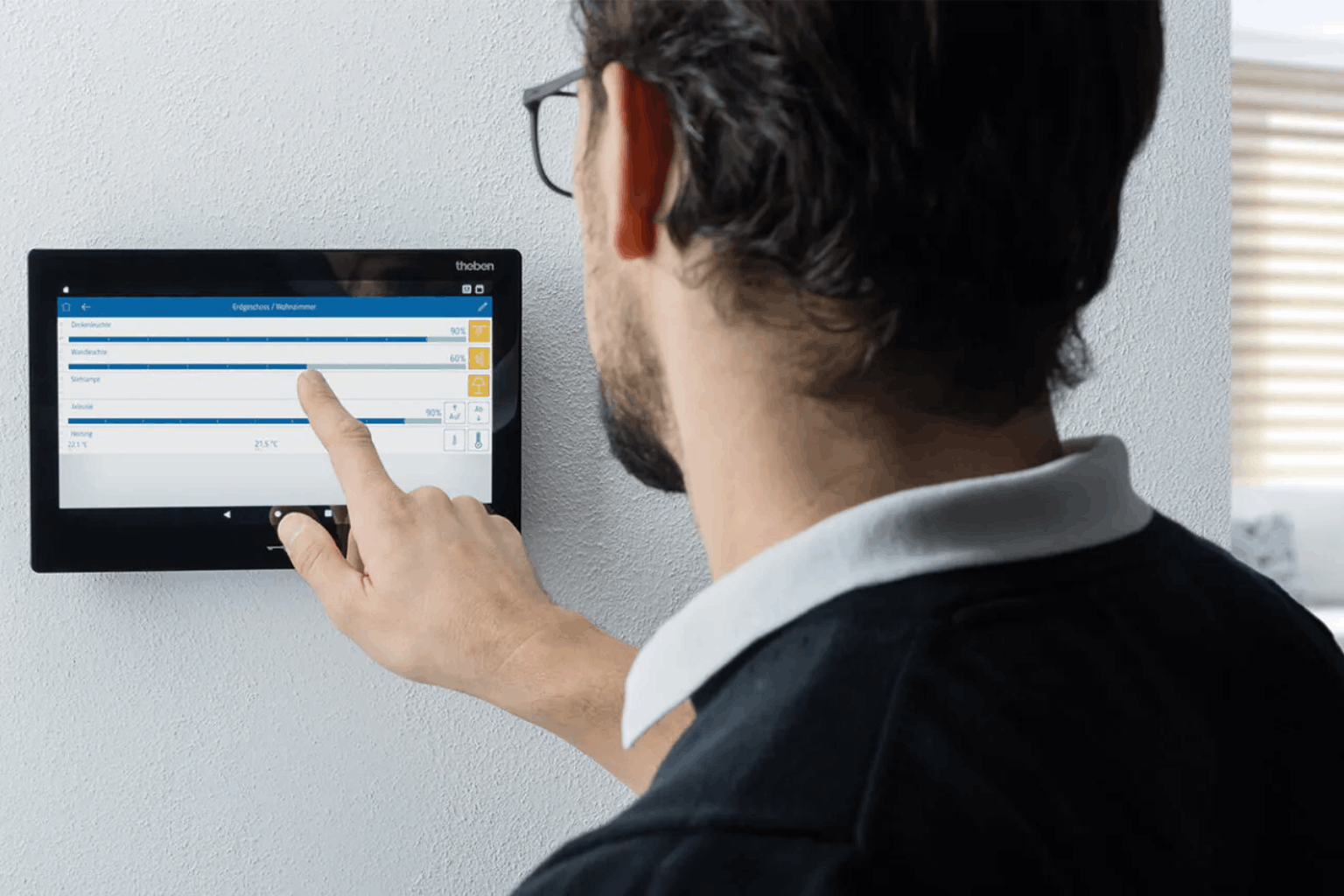 Man using wall mounted Theben smart home touchscreen.